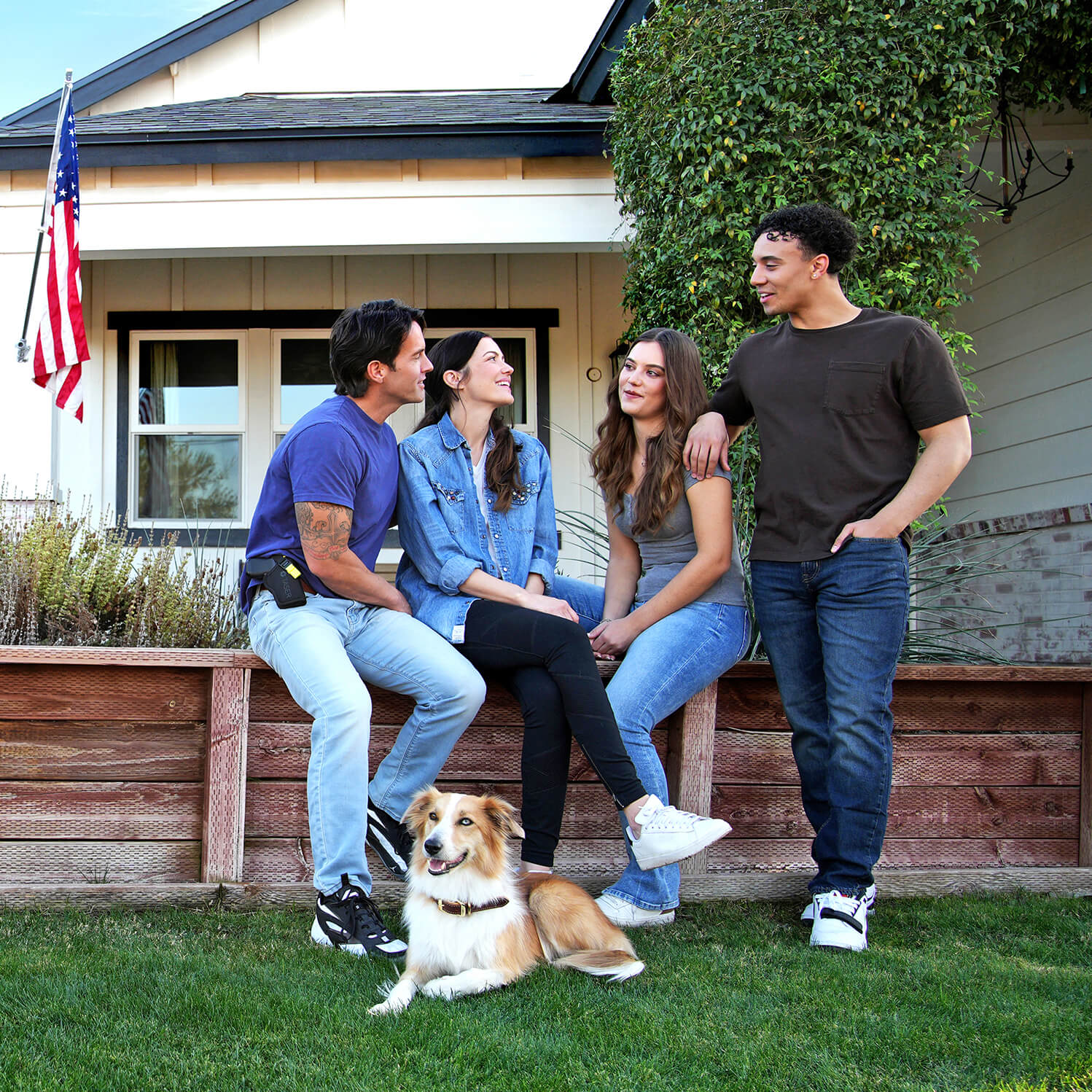 Group outside suburban home with U.S. flag and dog on lawn; one man carries holstered TASER Pulse 2, showing everyday safety.